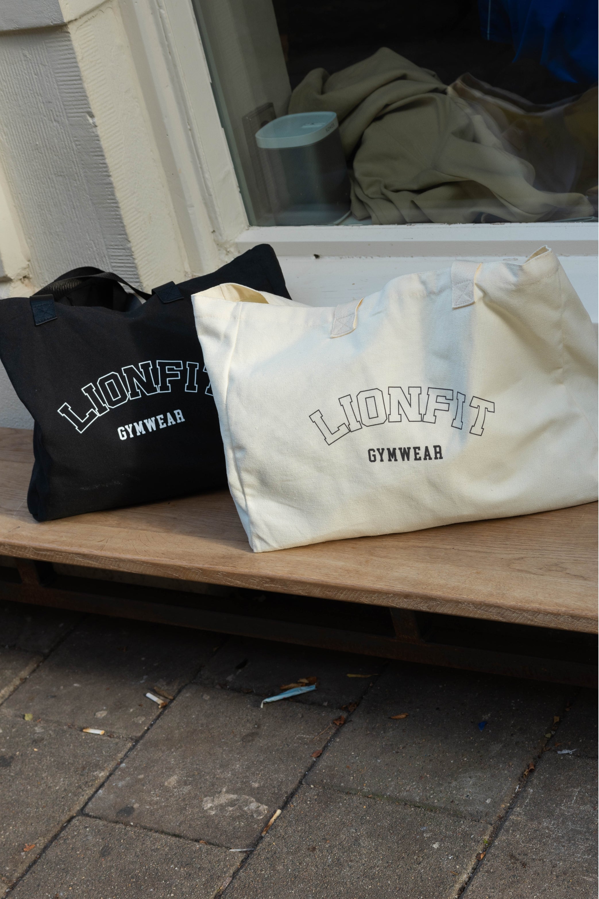 Vrouw met de Essential Totebag Beige van Lionfit Gymwear in sportieve outfit, buiten bij daglicht. Grote katoenen shopper tas perfect voor sportschool, strand of dagelijks gebruik, gemaakt van duurzaam gerecycled materiaal.