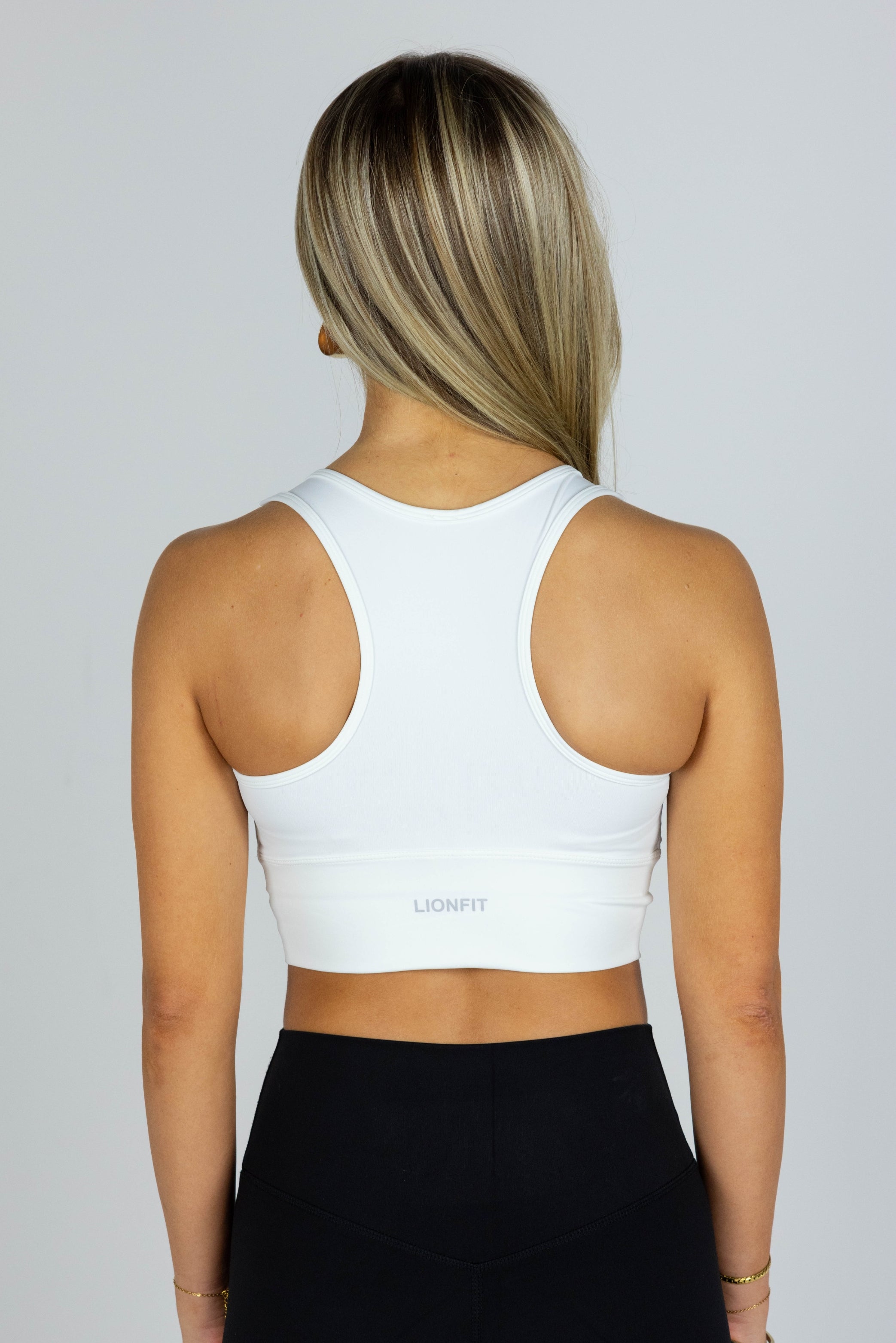 Lionfit Essential Bra White Long - Naadloze witte sport-bh met lange fit voor dames, biedt extra ondersteuning en comfort, ideaal voor intensieve trainingen en dagelijkse activiteiten, gedragen door model van 164 cm