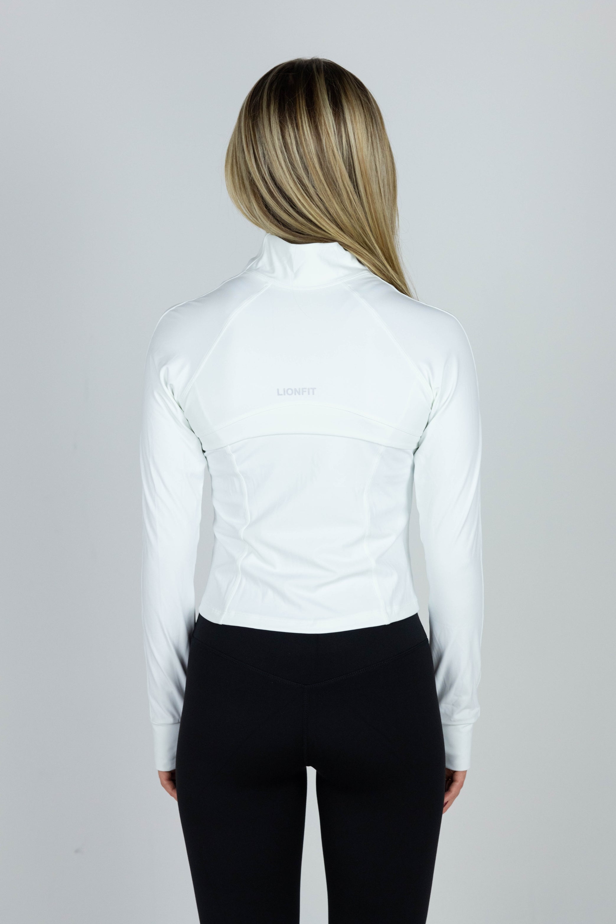 Vrouw draagt Lionfit Essential Zip Vest White, naadloos wit sportvest met ritssluiting, ideaal voor workouts en casual wear, comfortabele pasvorm en ademend materiaal