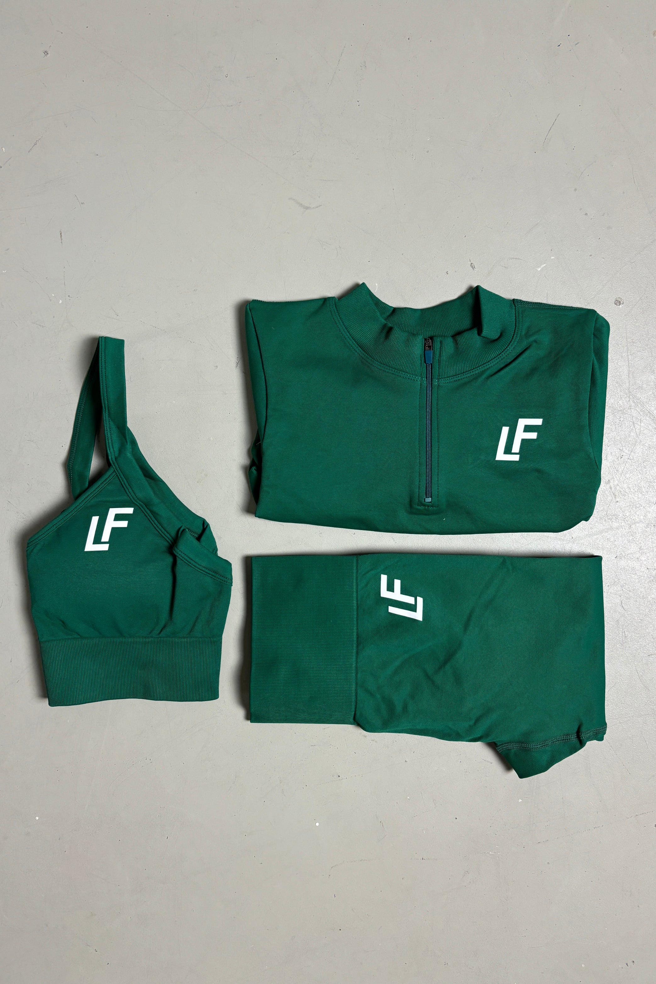 Kion Forest Green sport set voor dames van Lion Fit Gymwear, bestaande uit een groene sporttop met halve rits, sport-bh en leggings. Perfect voor fitness en yoga.